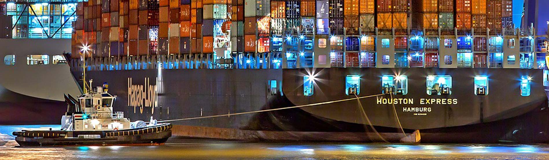 A brightly lit container ship at night