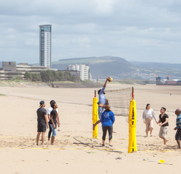 Students on the beach playing volley ball.