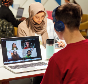 An image of two students studying, with one listening to a webinar
