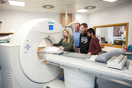 Students gathered around a CT scanner 