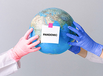 gloved hands holding globe with pandemic sticker