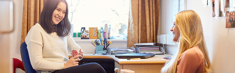Students chatting in bedroom next to desk