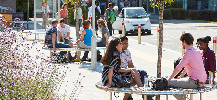 Students sat on benches chatting in the sun 