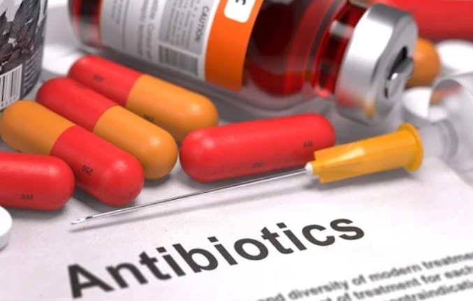Various antibiotic drugs tipped out of bottle with text description of the word antibiotics