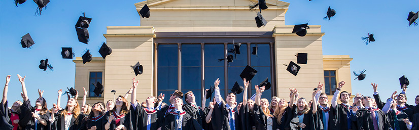 Students Throwing Mortar Boards in front of the Great Hall with Blue Sky on Graduation Day