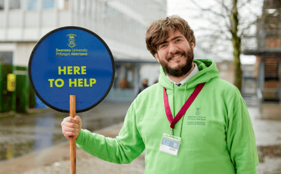 Student ambassador holding a 'Here to Help' sign