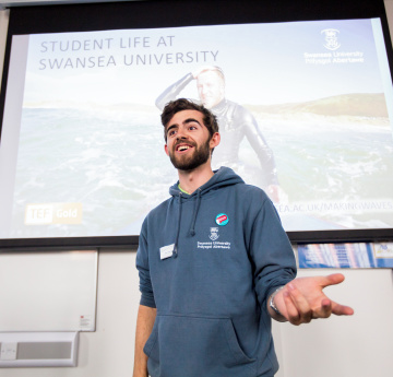 An image of a student delivering a presentation to visitors.
