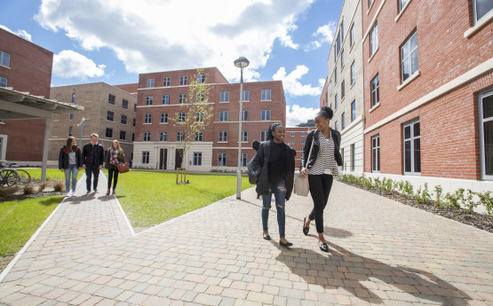 Students walking around the Bay campus accommodation buildings on a sunny day