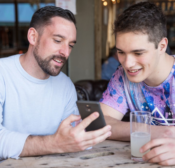 Two males laughing at something on a phone