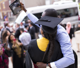 A parent and child at graduation taking a selfie