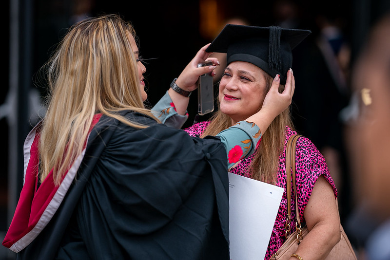 Image of student placing mortarboard hat on guardian/parent.