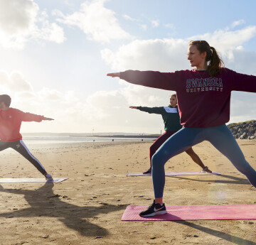 Students doing yoga on the beach