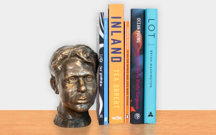 Six books on this year's shortlist next to a bust of Dylan Thomas