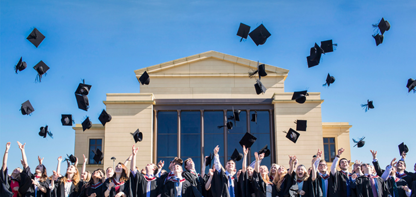 A large group of students throwing their mortarboards in the air 