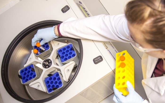 Picture shows samples being put into a centrifuge, an instrument used to separate sample components. 