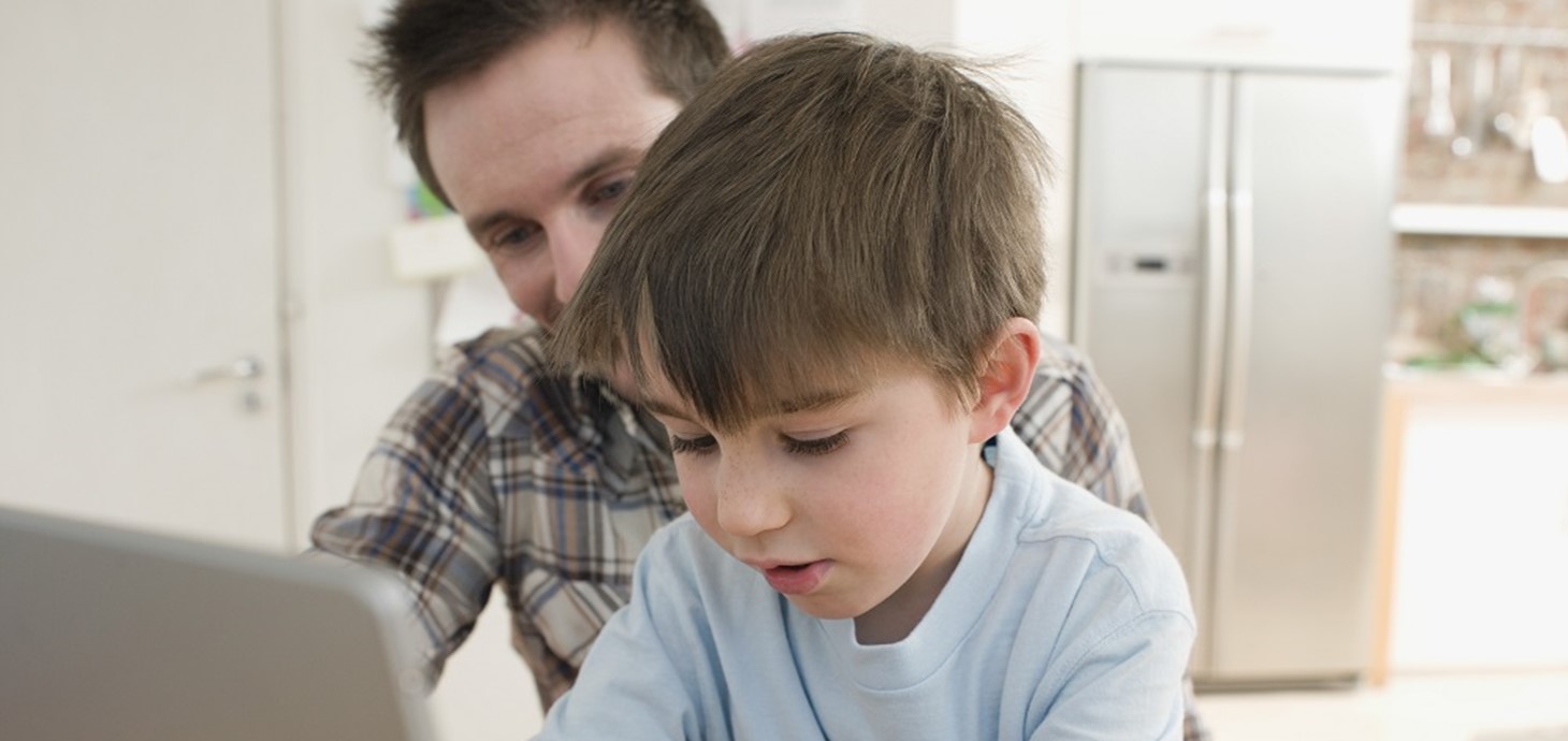 A boy at a computer with his father