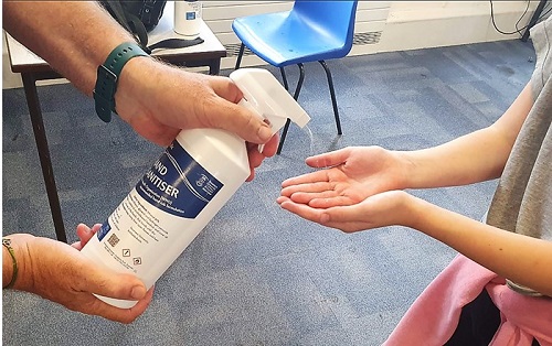 A pupil receives Swansea Uni hand sanitiser to clean hands