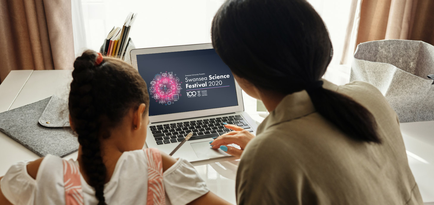 A mother and daughter sat at desk using a laptop visiting the Swansea Science Festival website 