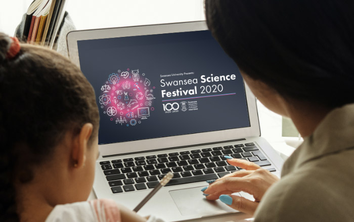 A mother and daughter sat at desk using a laptop visiting the Swansea Science Festival website 