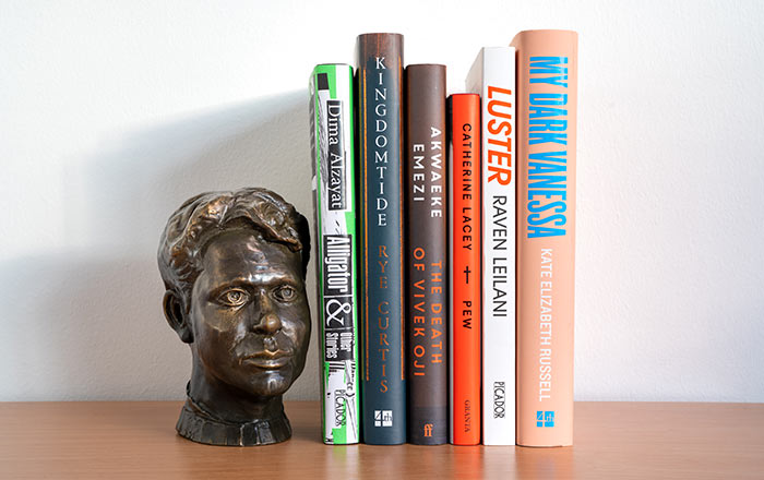 The six shortlisted books on a shelf next to a bust of Dylan Thomas