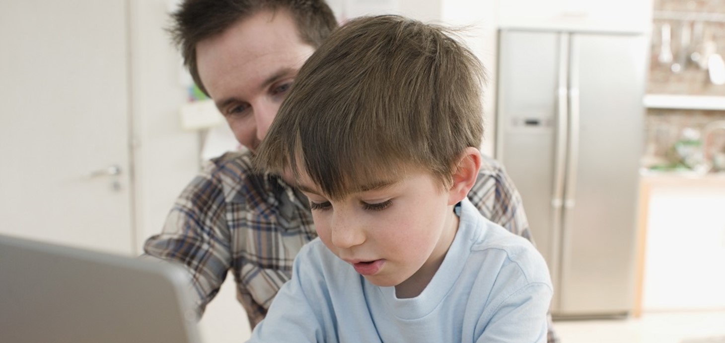 Father and son at a computer:  children who live with a parent who has depression are more likely to develop depression and to not achieve educational milestones, according to a new study