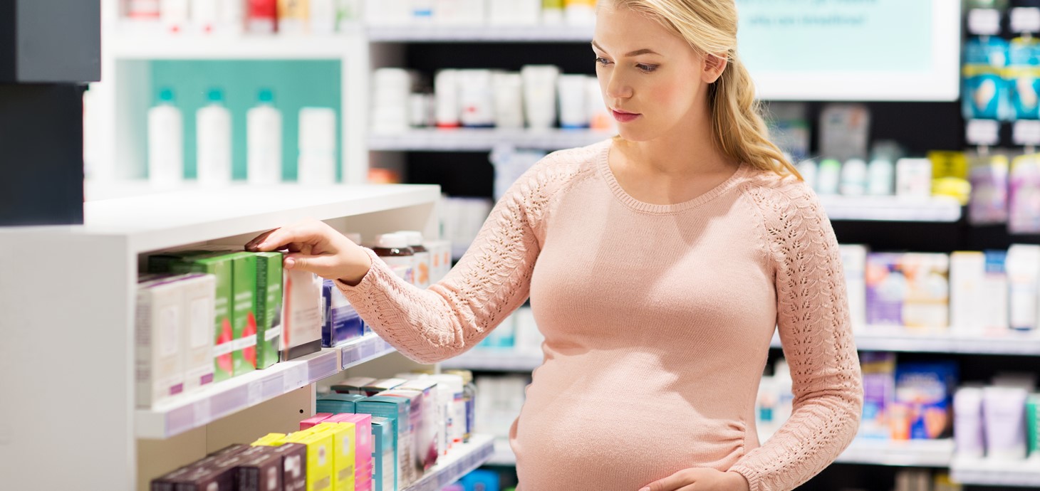 Pregnant woman in a pharmacy looking at medication