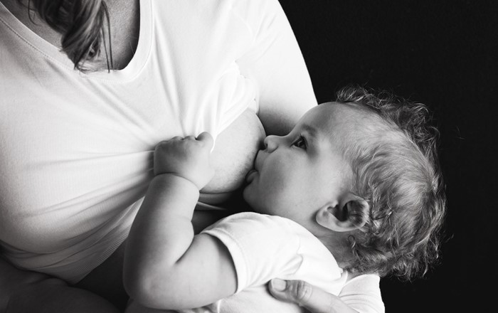 Baby being breastfed by its mother who is wearing a T-shirt