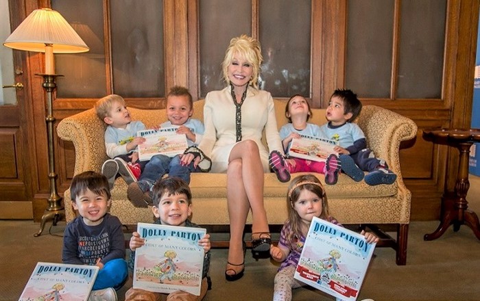 Dolly Parton with children and books; the Imagination Library has given more than 185 million books to children, and the Swansea research is the largest survey of its effectiveness ever carried out. Credit: Dollywood Foundation UK