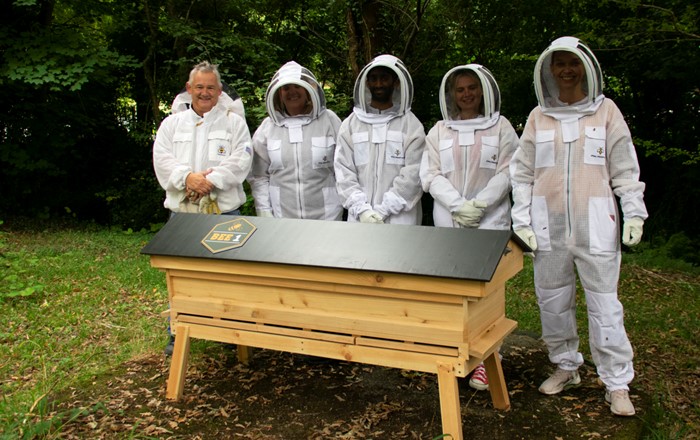 Bee1 founder Mark Douglas and the beekeeping volunteers standing next to the hive on Singleton Campus.