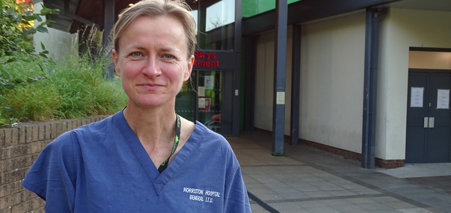 Woman in scrubs standing outside building