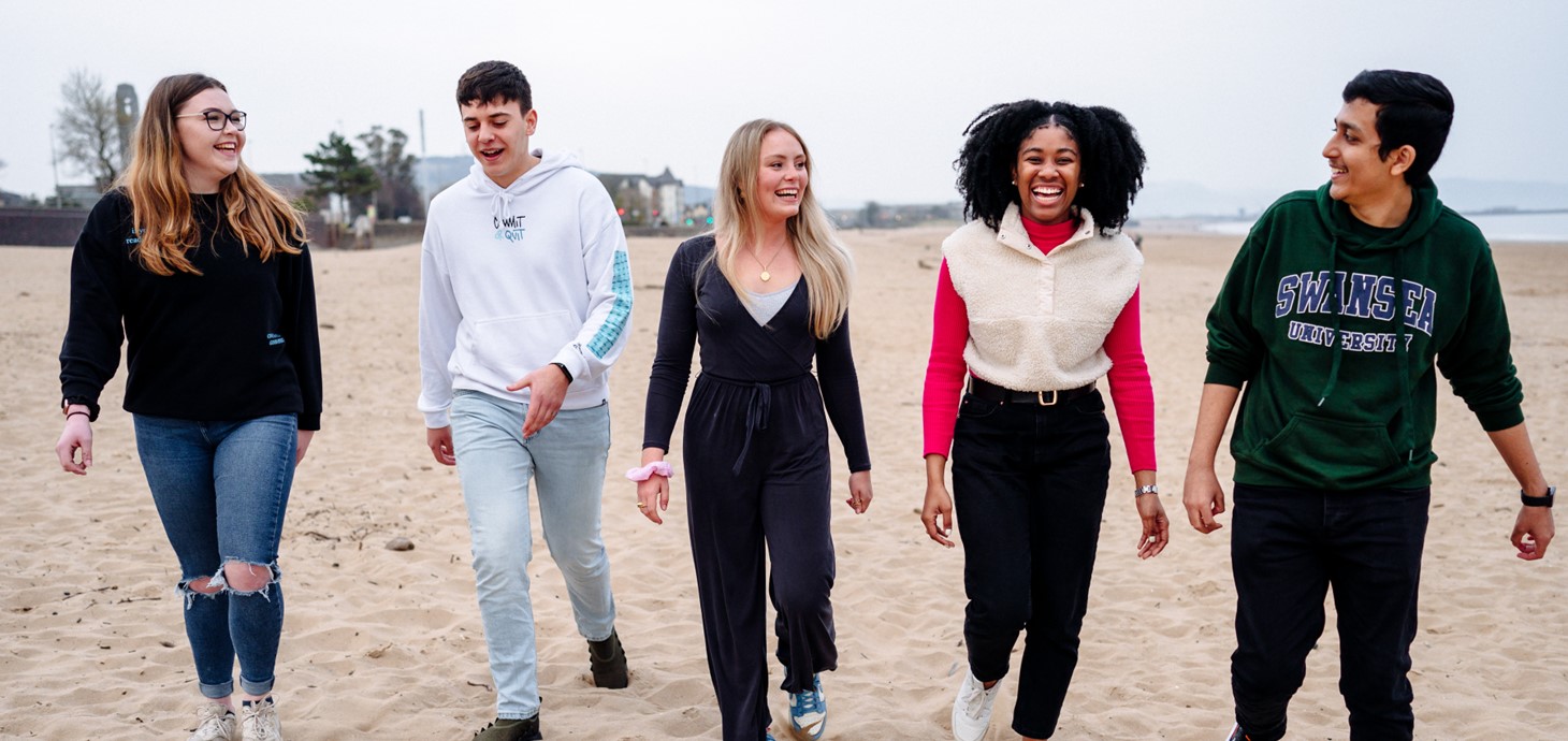 A group of students walking on Swansea beach 