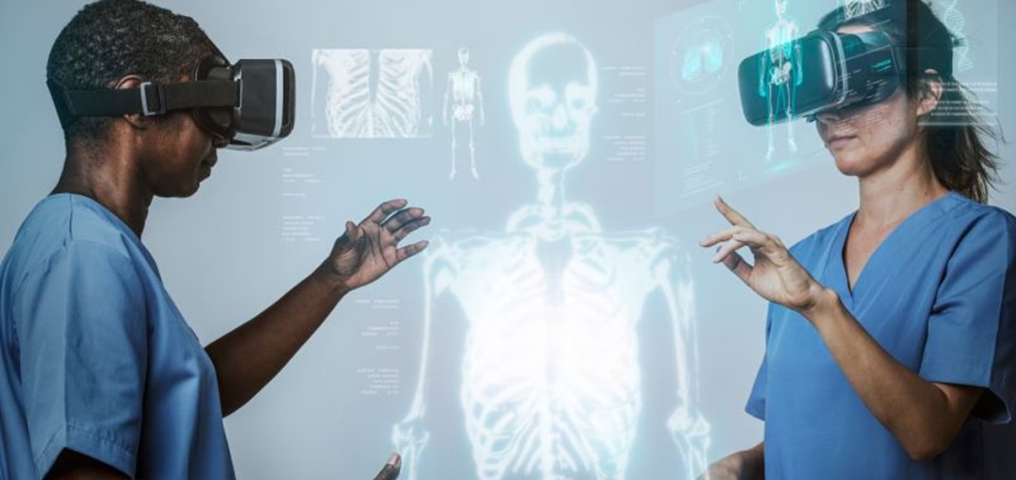 Two people in medical scrubs wearing VR headsets by an image of a skeleton