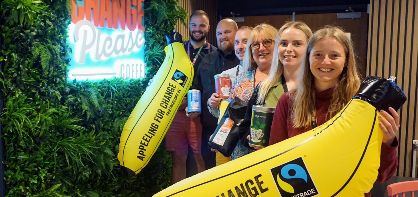 Group of six smiling people indoors holding Fairtrade products