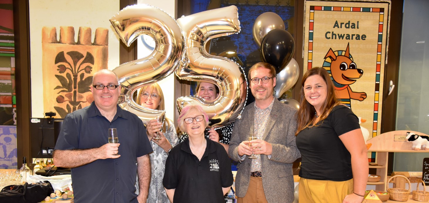 A photo of staff and guests during the Egypt Centre's anniversary event. Behind them are two balloons which make '25'.