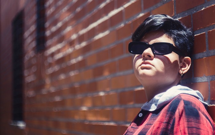 Person standing in front of a wall wearing dark glasses