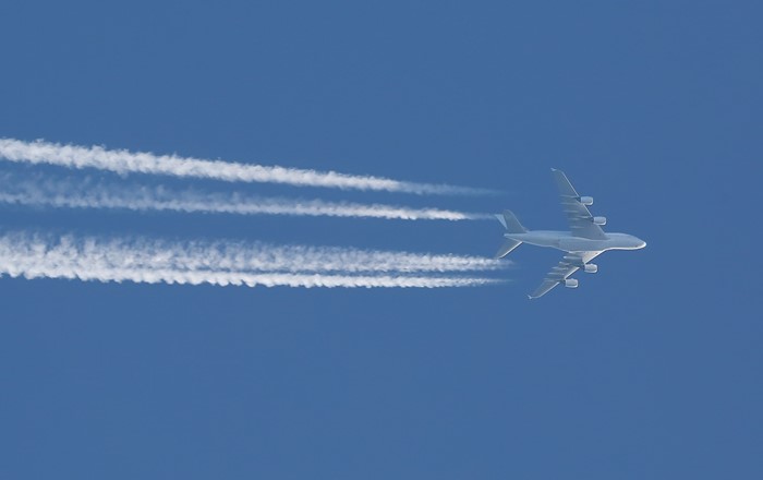 Jet plane pictured flying across a blue sky leaving a series of vapour trails behind