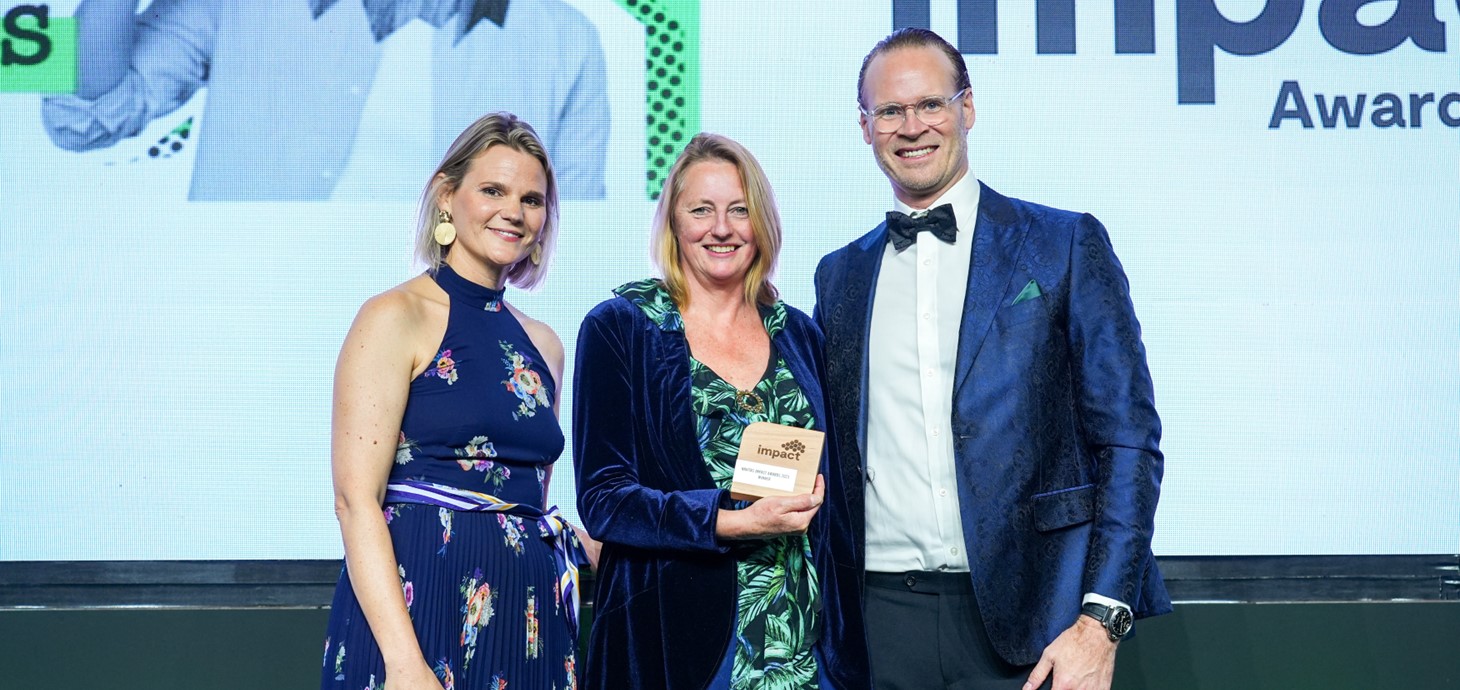 Emma Frearson Emmanuel, Associate Director of Marketing, Recruitment and International at Swansea University, on stage holding the award, standing next to (left) Julia Lambo, Director of Corporate Communications and ESG at Navitas, and (right) Scott Jones, Group CEO at Navitas. 