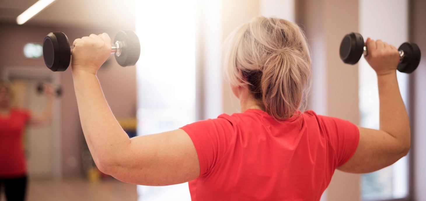 Woman with her back to the camera lifting two hand weights 