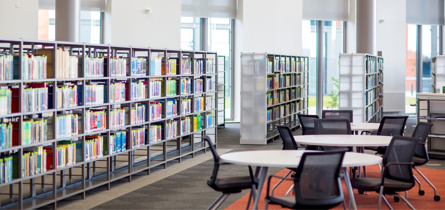 A photo showing the inside of Swansea University’s Bay Campus Library. There are bookshelves and empty tables.