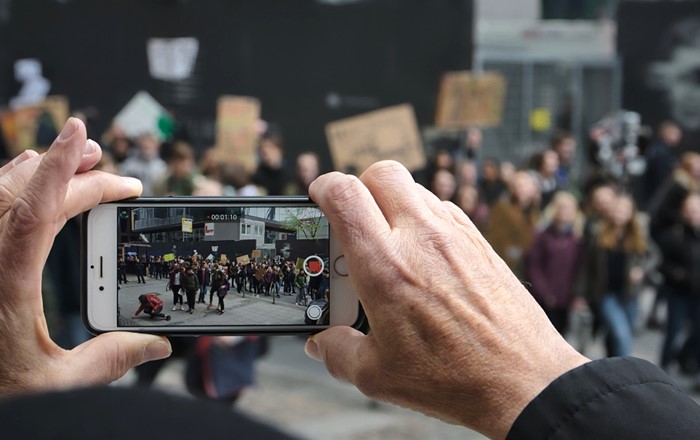 Someone taking a picture of a protest. Open-source material, including pictures, has become increasingly vital in legal proceedings and fact-finding missions. This is particularly so in the realms of human rights, humanitarian law, and international criminal law
