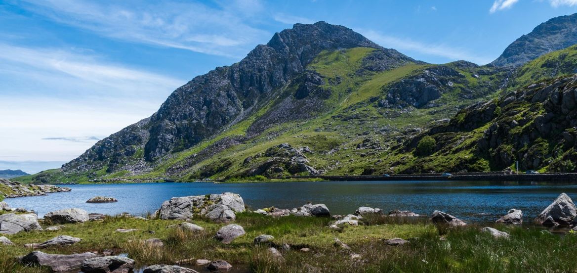 Area of inland water with rocks and mountain in background against blue sky