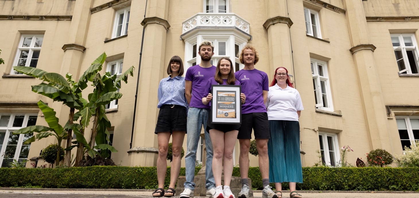 Five people standing outside building, three central people wearing running kit.