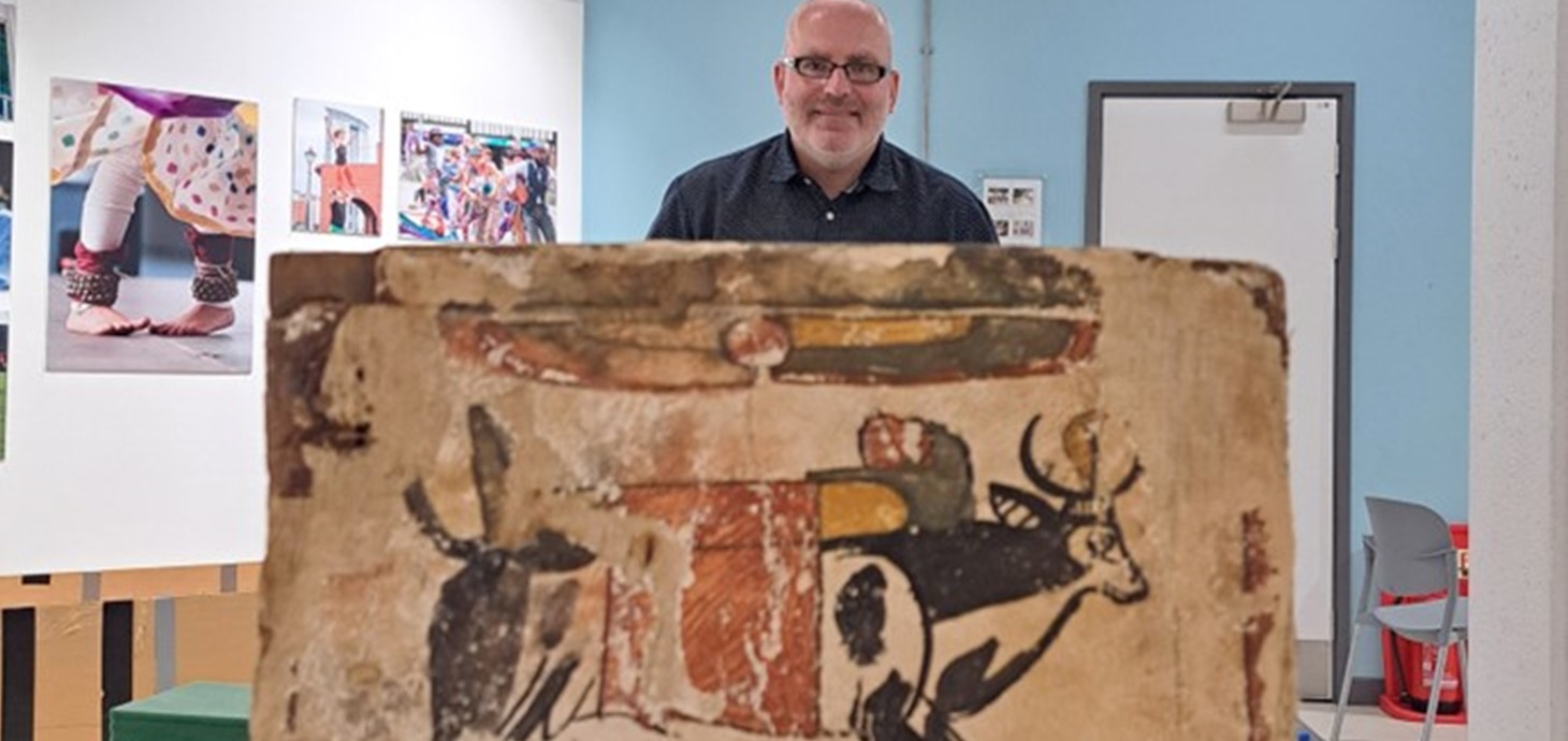 Man standing behind the end of a decorated wooden box