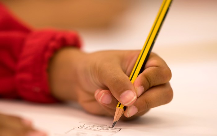 A close-up of a child's hand holding a pencil