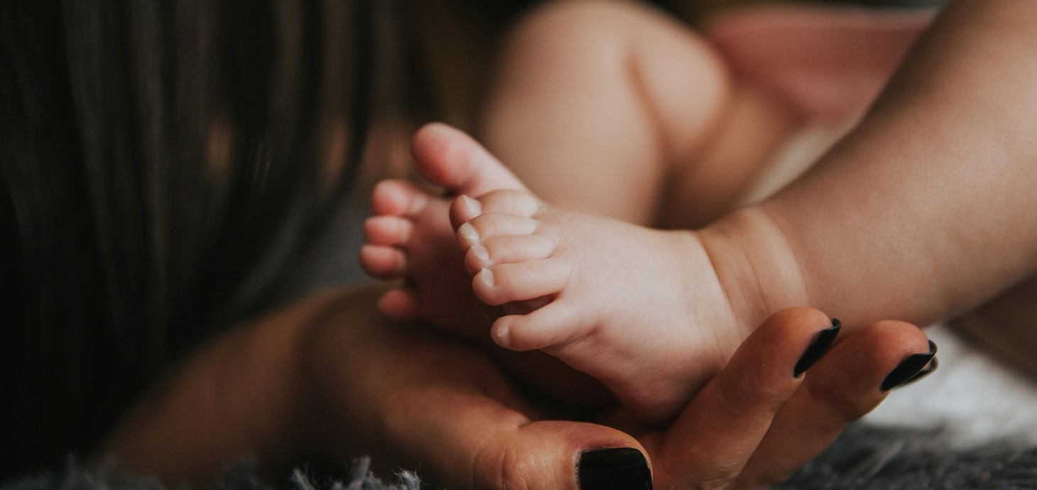 Close of a baby's feet nestling in a woman's hand