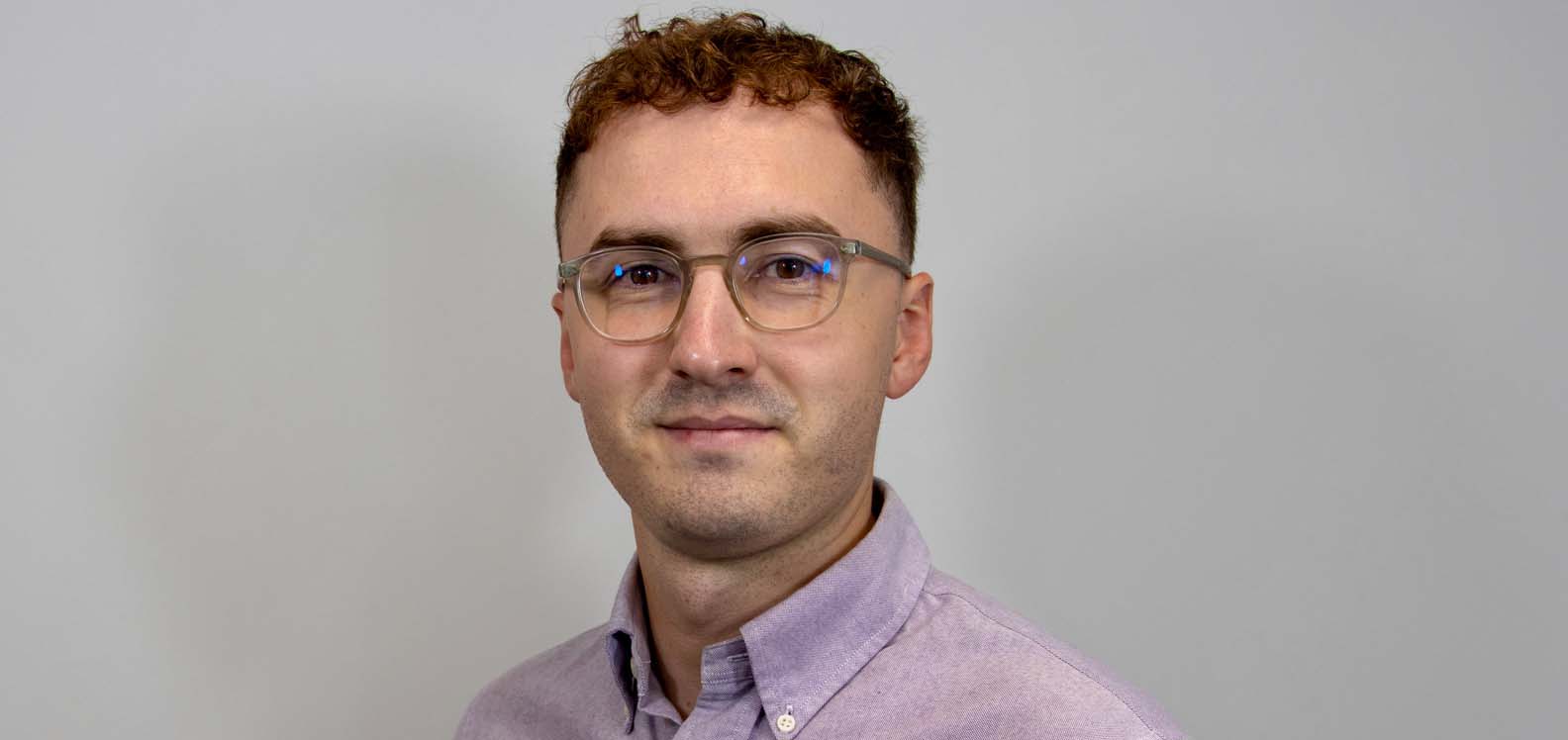 Man wearing shirt standing in front of plain background