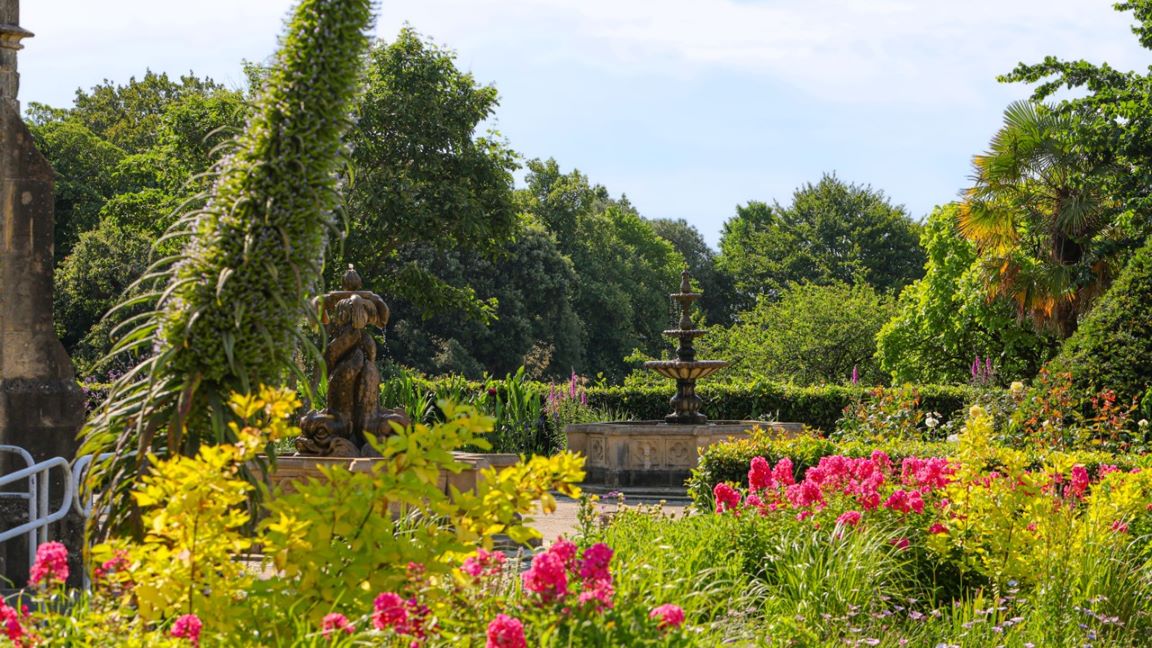 Ornamental garden with flowers, shrubs and stone fountain 