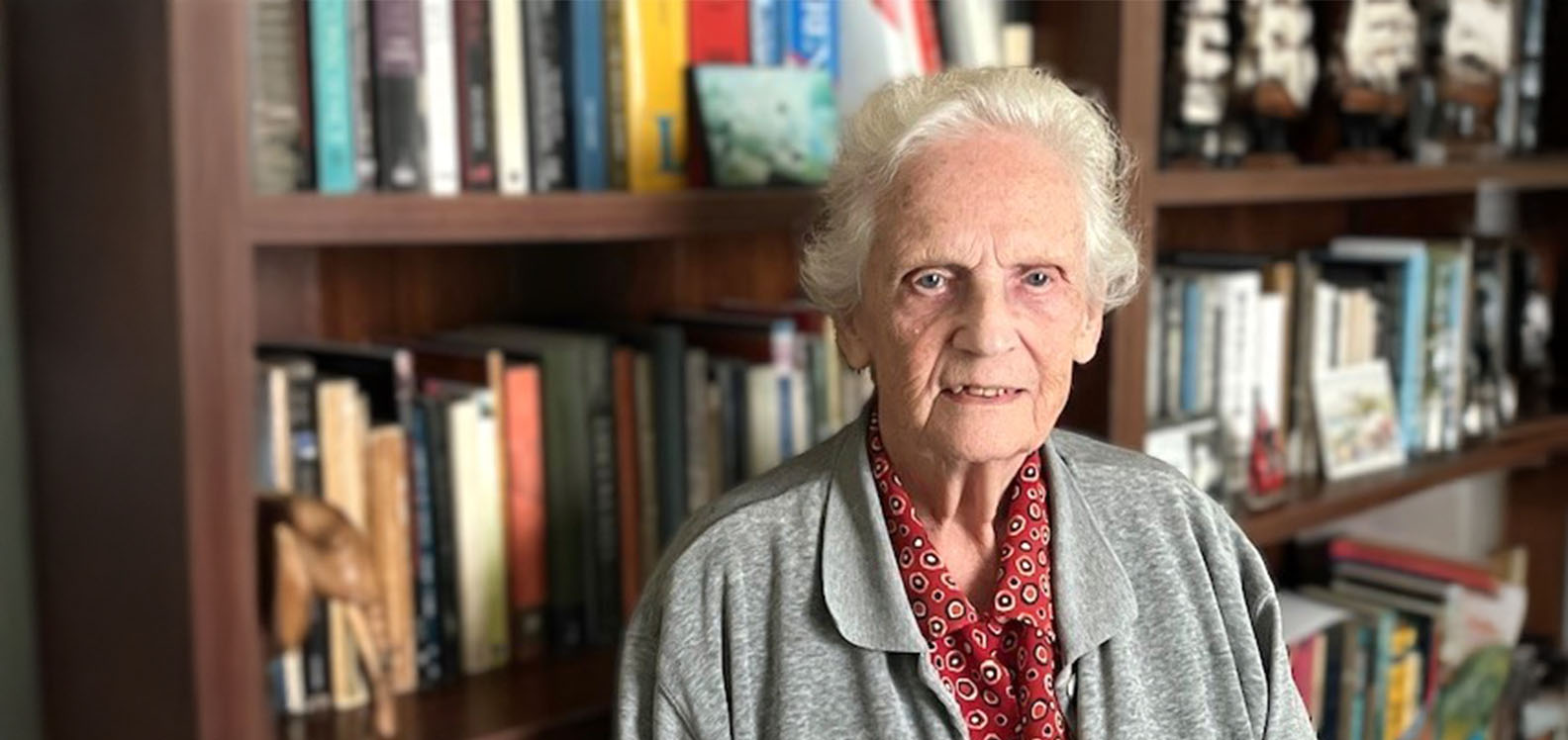 Elderly woman sitting in front of a bookcase