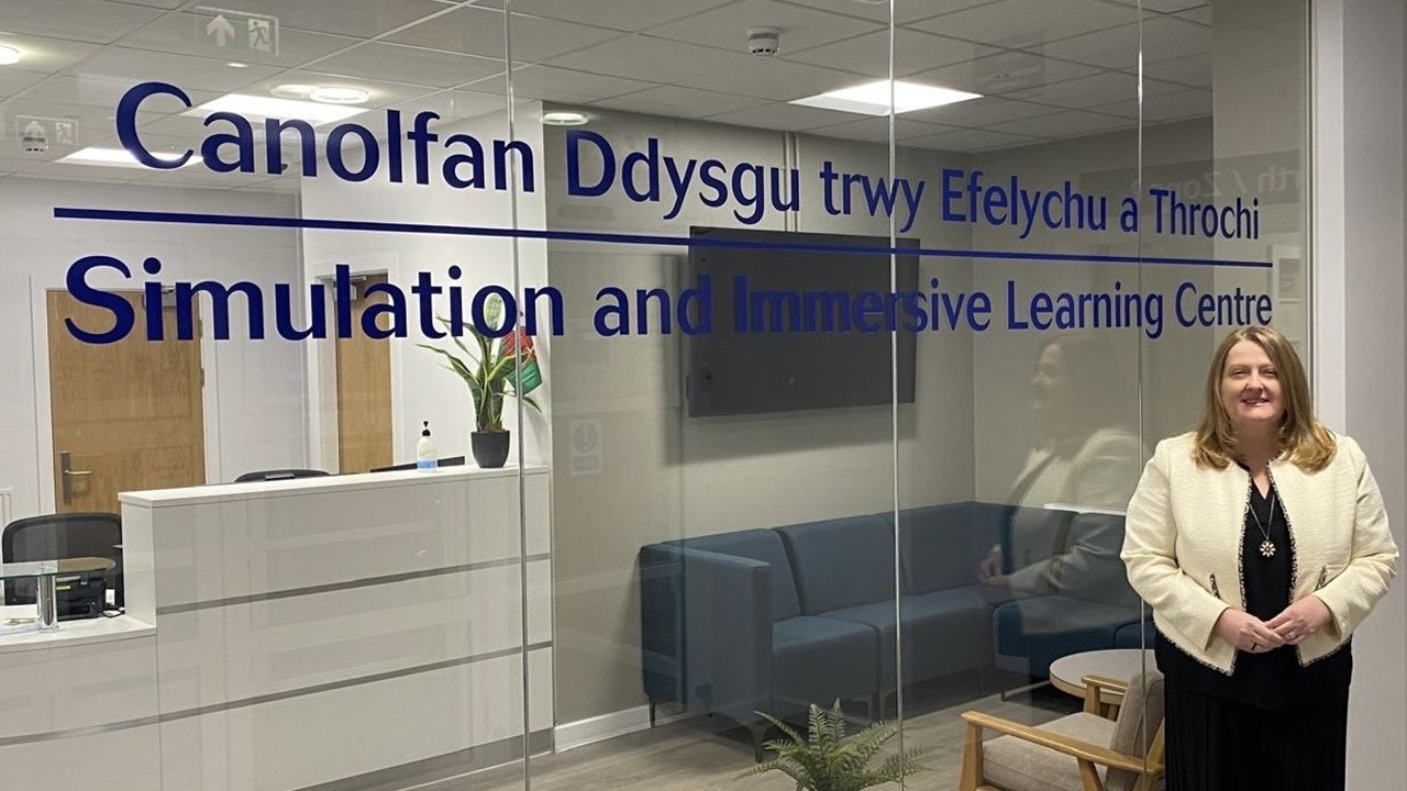 Woman standing indoors in front of glass partition 