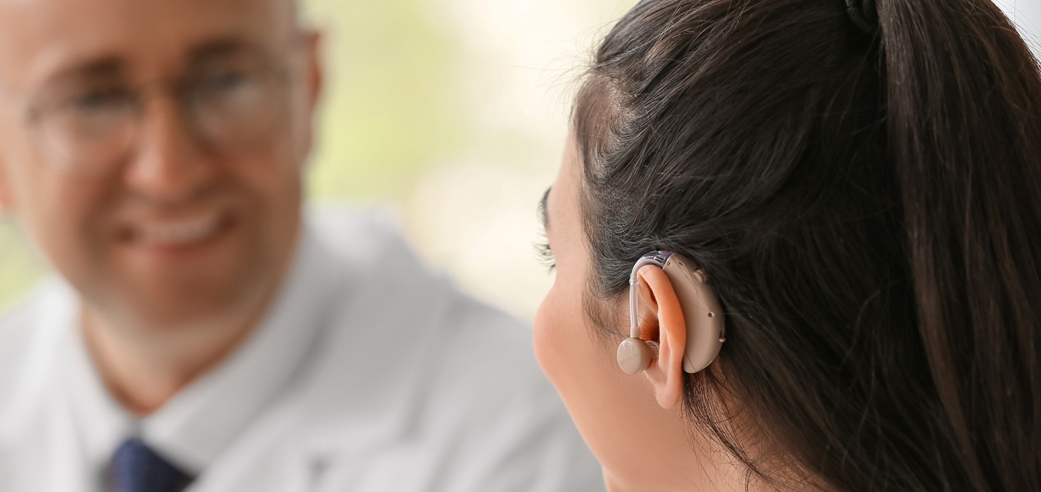 A young woman wearing a hearing aid talking to a doctor